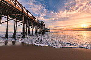Balboa Pier at sunset with waves and colorful sky in Newport Beach California