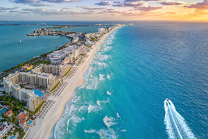 Aerial view of Cancun beach with turquoise water and a small boat along the shoreline in Mexico