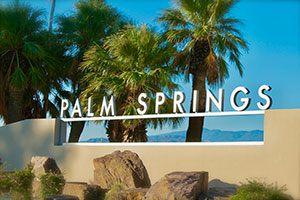 Palm Springs welcome sign with palm trees in the background