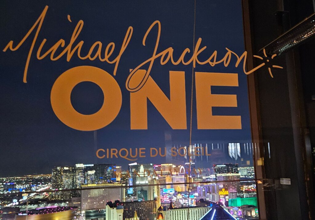 Michael Jackson ONE by Cirque du Soleil sign overlooking the Las Vegas skyline and illuminated Strip.
