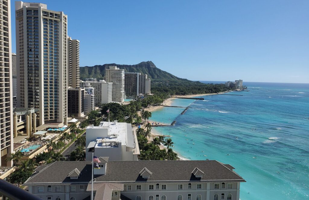 A luxury beach resort view during the day of Waikiki Beach with a veiw of Diamond Head.
