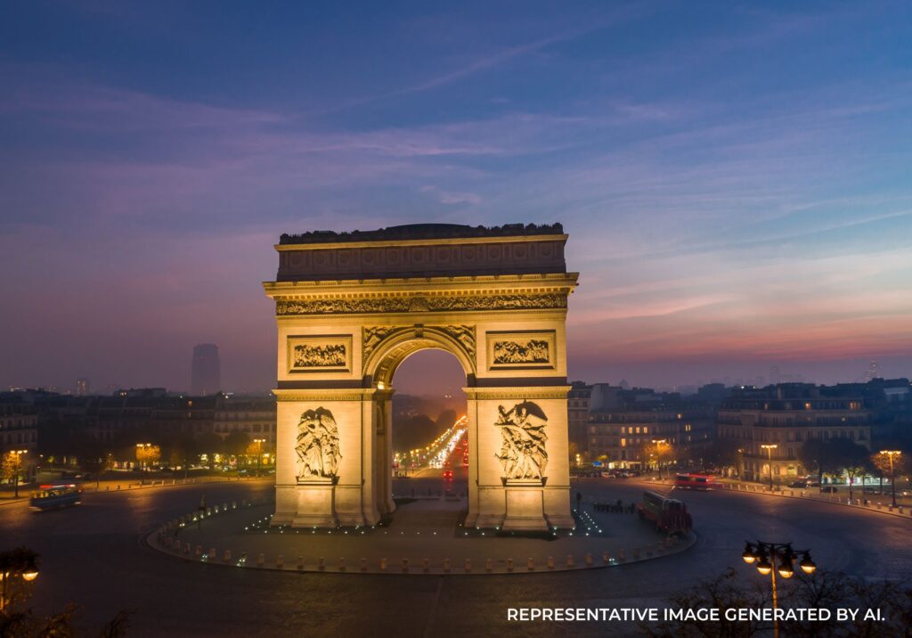 Twilight view of the Arc de Triomphe surrounded by city lights and a glowing sky in Paris.