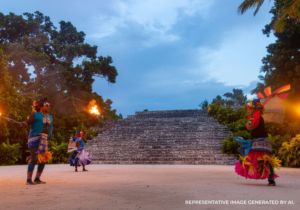 Performers holding flames during a cultural fire dance near ancient stone structures at twilight.