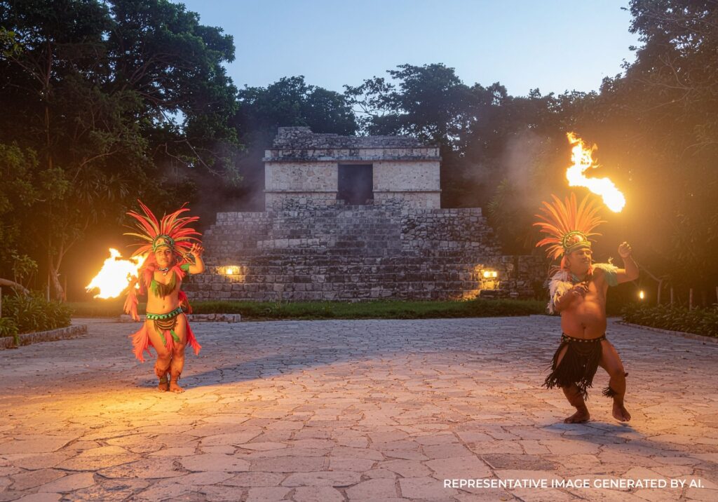 Cultural performers dancing with flames in front of ancient steps during an outdoor ceremony.