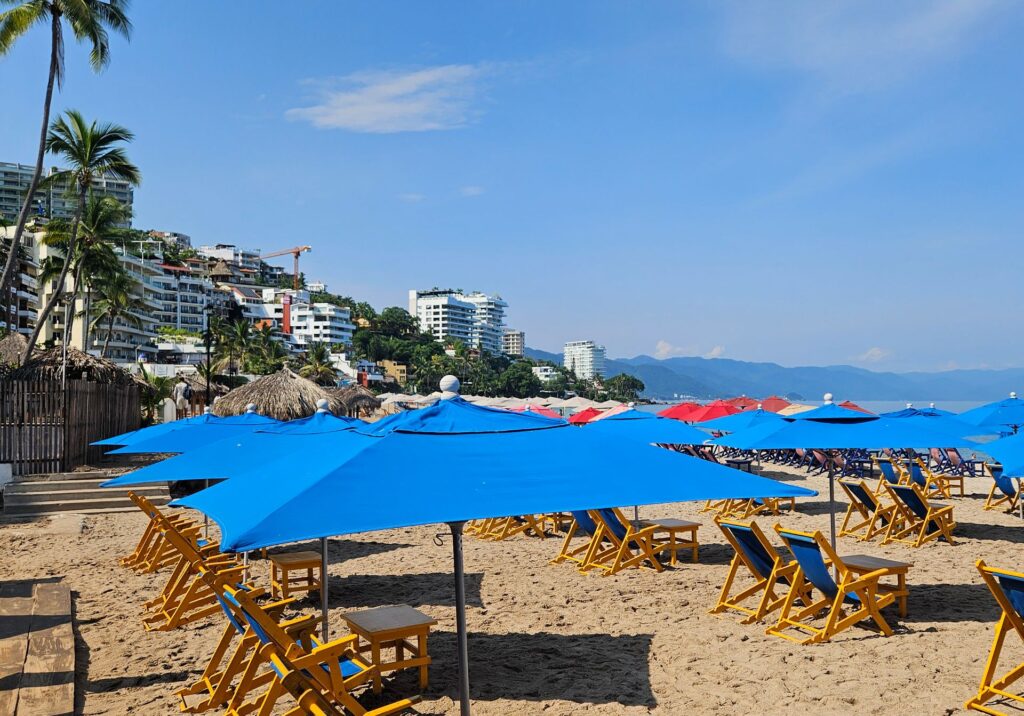 Rows of blue beach umbrellas along the sandy shoreline in Puerto Vallarta