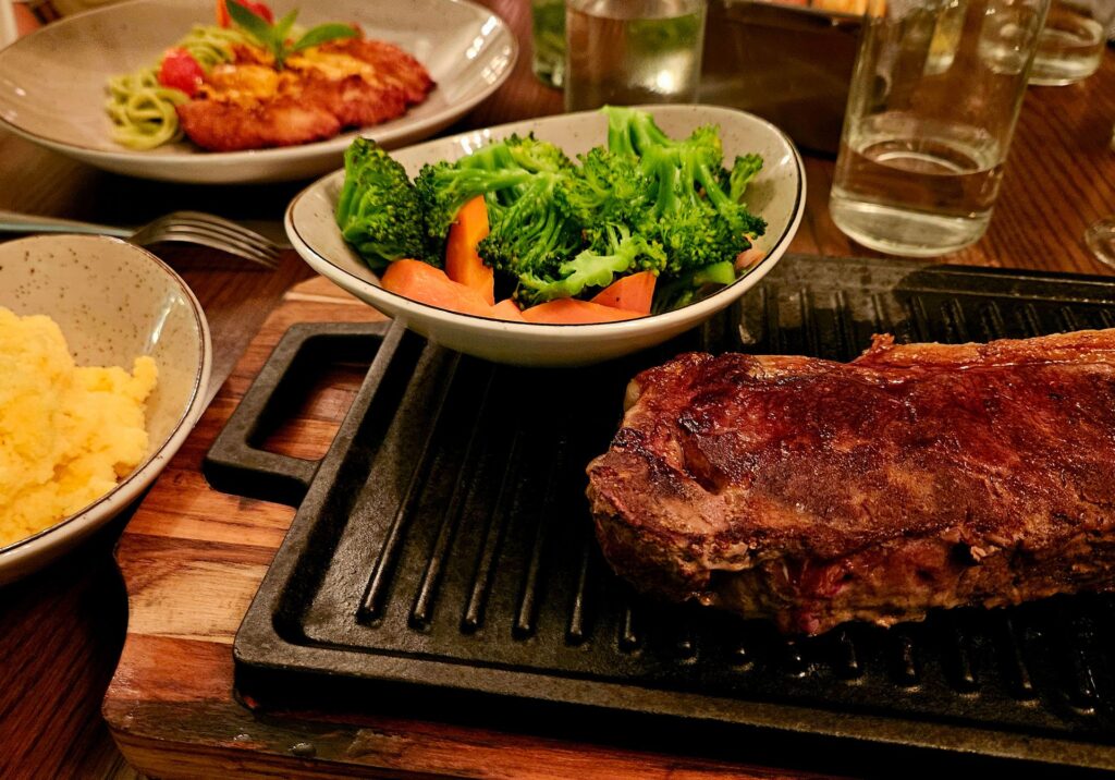 A sizzling grilled steak served with fresh sides at an outdoor Puerto Vallarta restaurant in Meixco