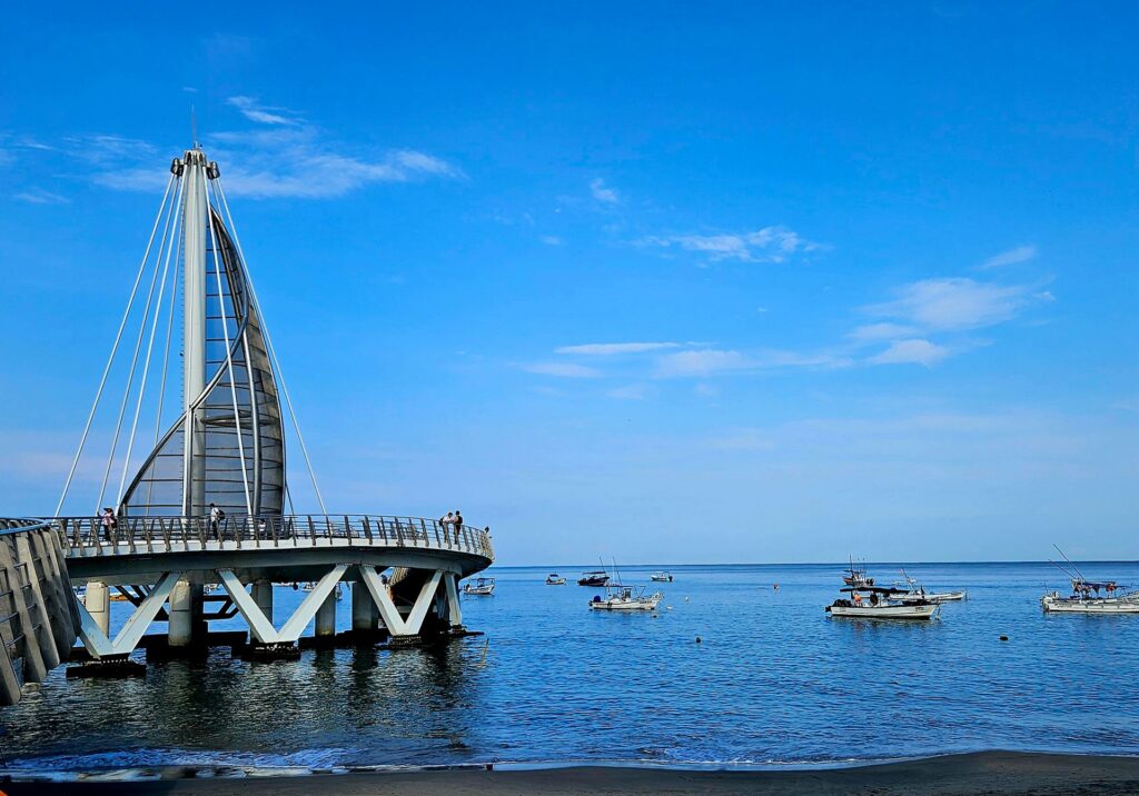 View of Los Muertos Pier stretching over the ocean with boats on the water in Puerto Vallarta