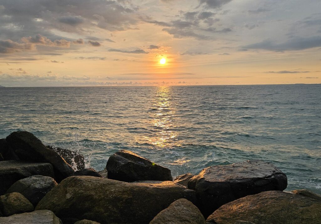 Warm sunset light reflects across the ocean and rocks along the Puerto Vallarta coastline
