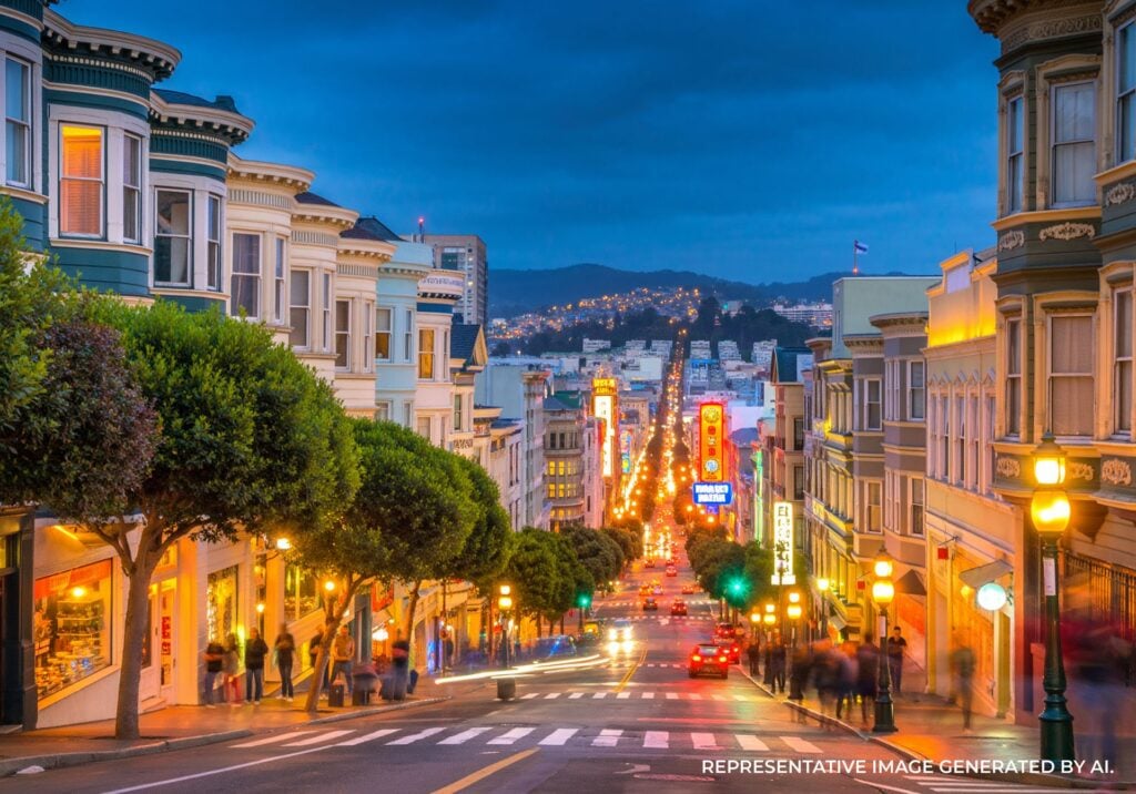 Evening view down Castro Street toward downtown San Francisco with rainbow flags and city lights.