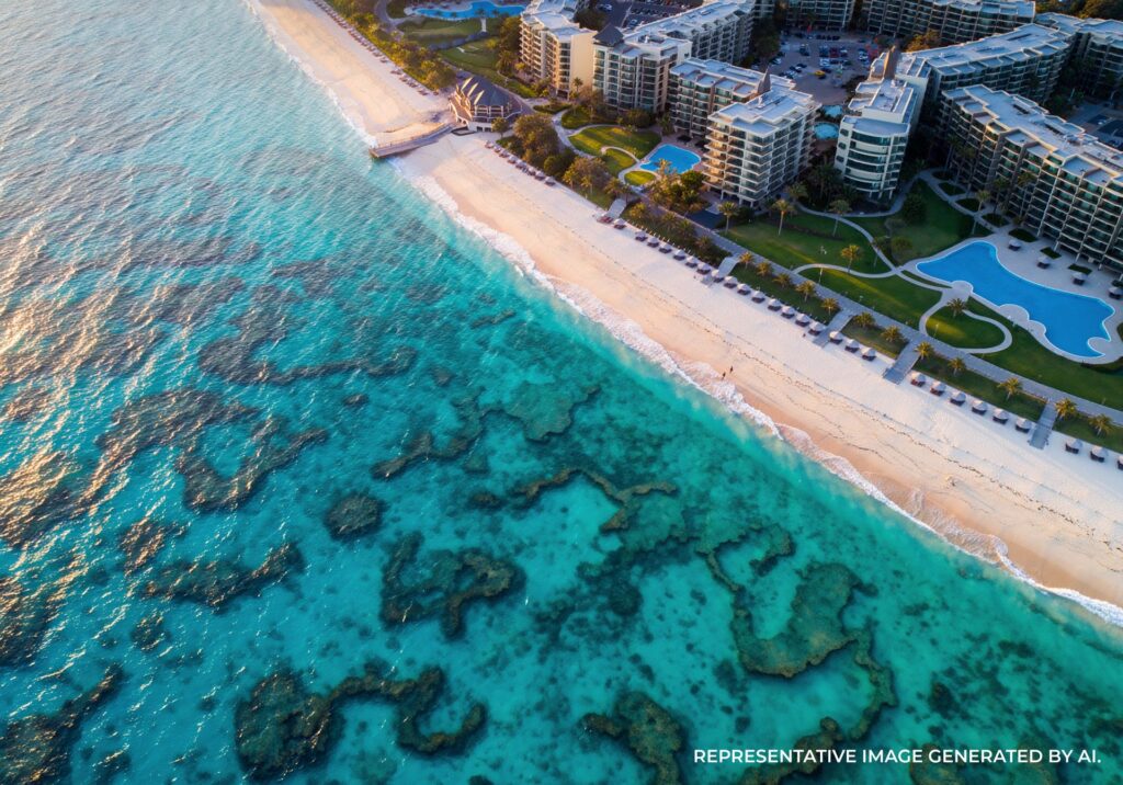 Aerial shot of a Sydney beach with turquoise water, soft sand, and nearby modern buildings.
