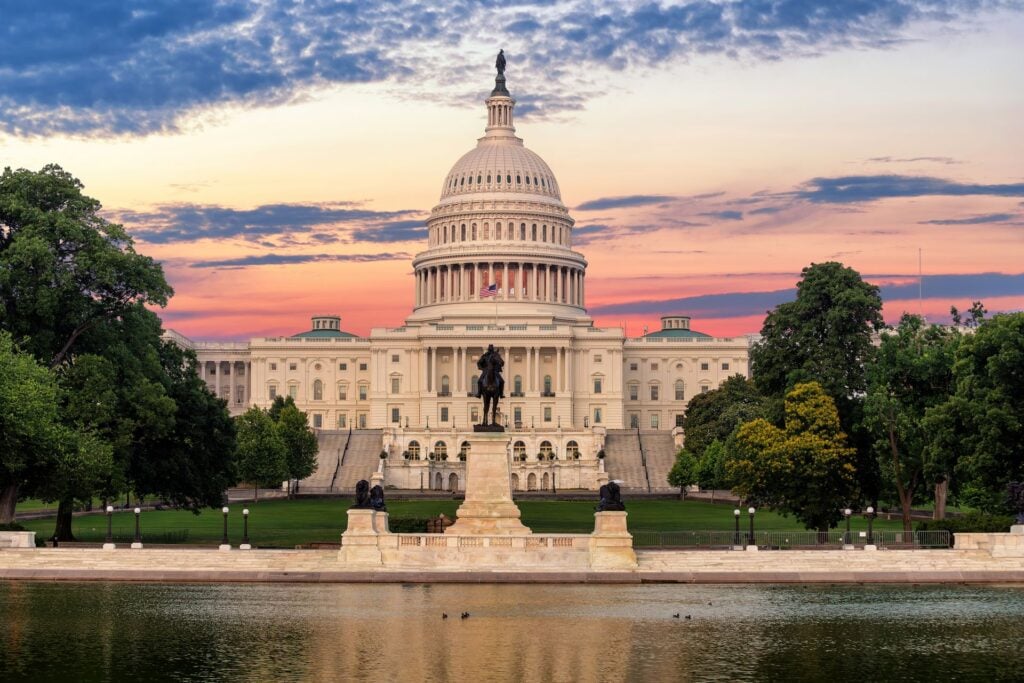 The United States Capitol Building in Washington, D.C. at sunset with colorful skies reflecting in the Capitol Reflecting Pool.