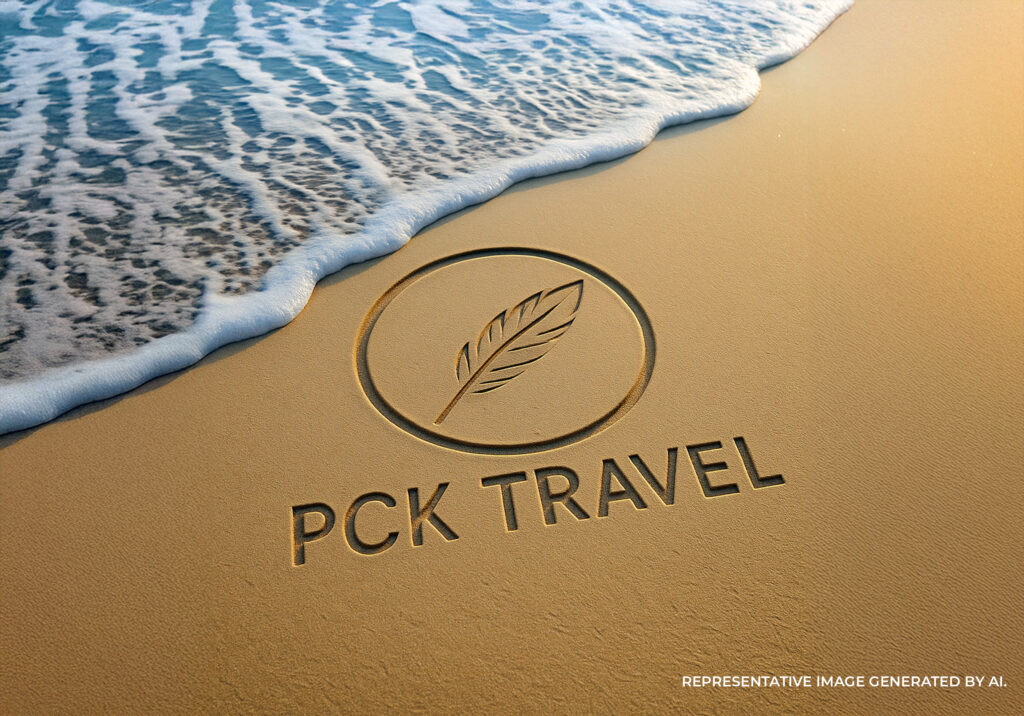 PCK Travel logo carved into beach sand near the shoreline San Diego with ocean waves approaching,
