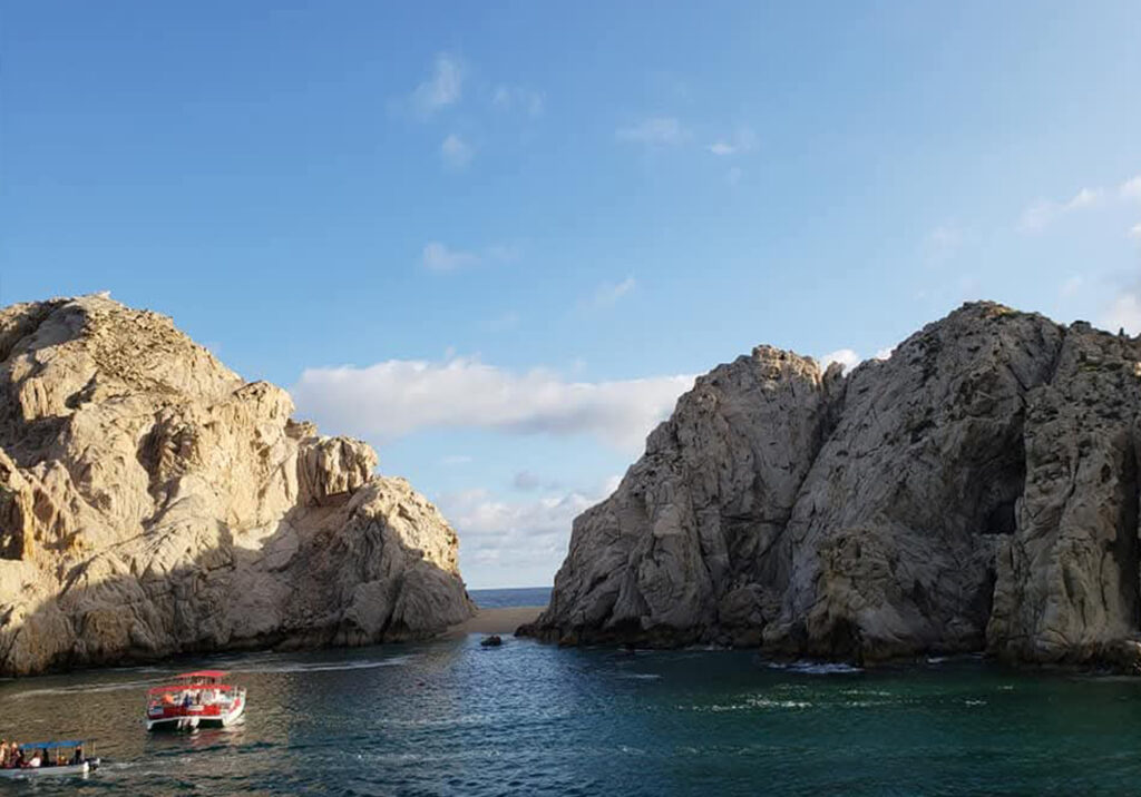 ocky coastline in Cabo San Lucas with deep blue water on a bright, sunny day.