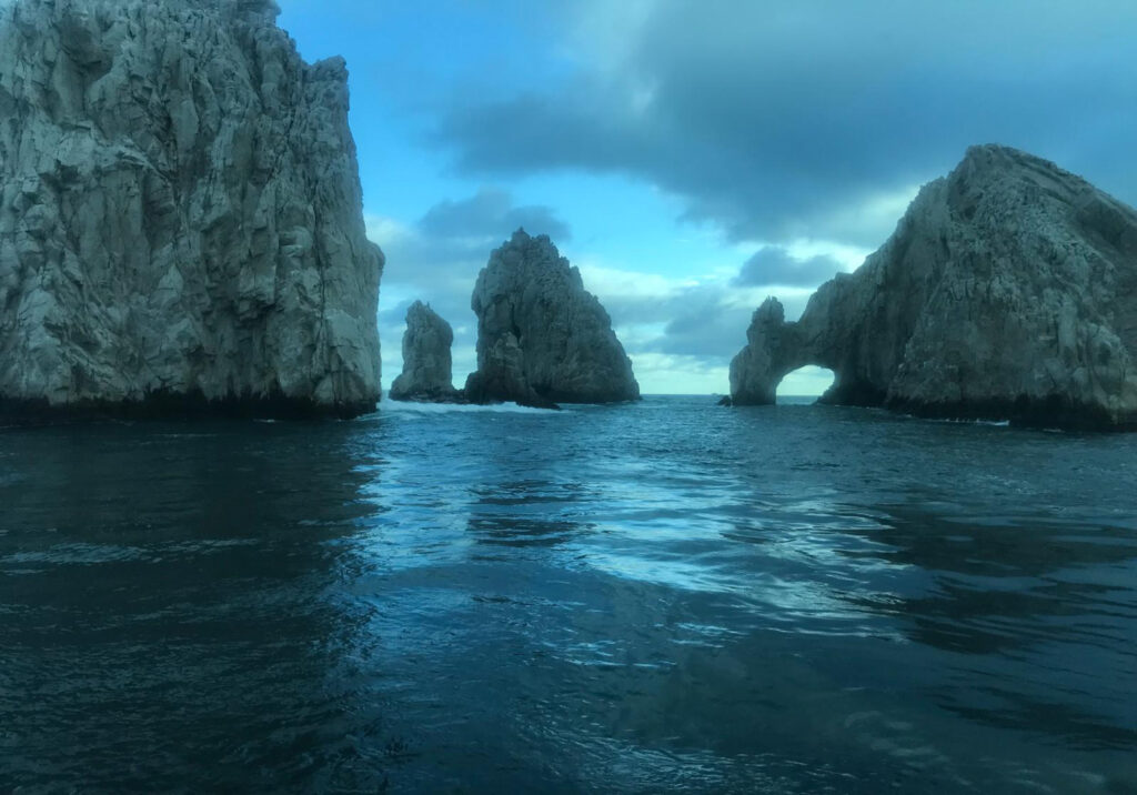Dramatic rock formations rising from the ocean near Cabo San Lucas at dusk