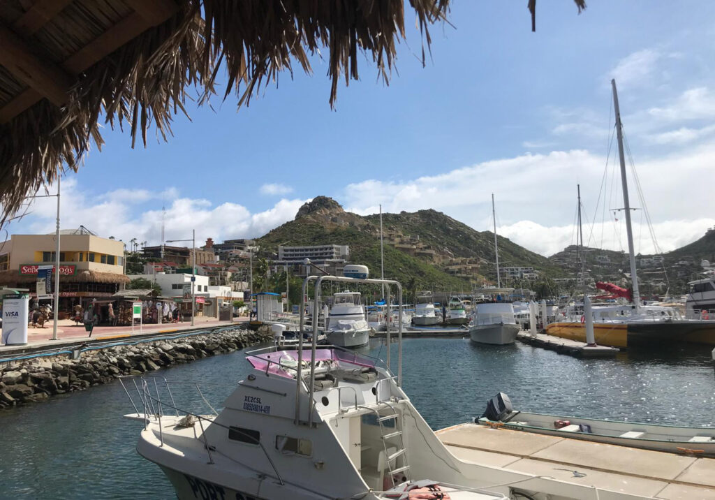 Boats docked at Cabo San Lucas Marina with surrounding hills in the background.
