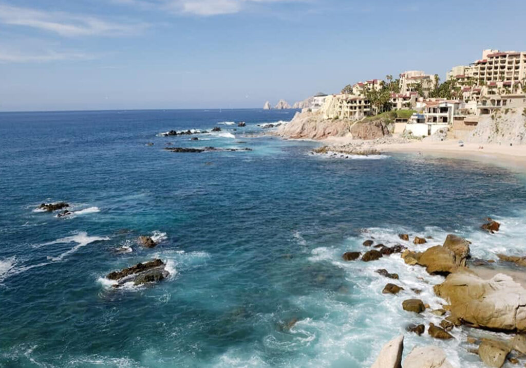 Rocky coastline and turquoise water along the shores of Cabo San Lucas on a bright sunny day.