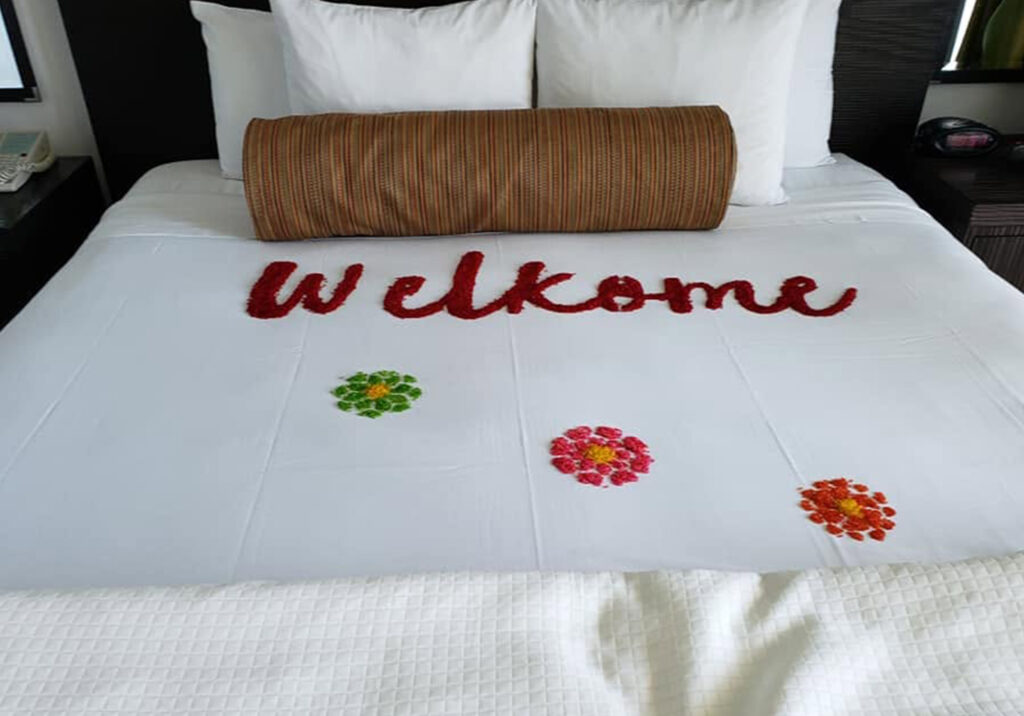 Bed decorated with flowers and a welcome message at a Cabo San Lucas resort.