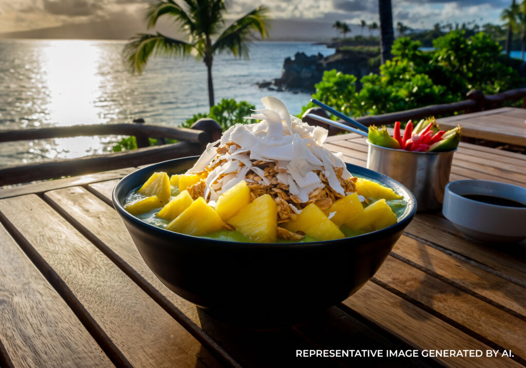 Bowl of mango shave ice with whipped cream and pineapple on a beach table in Kauaʻi.