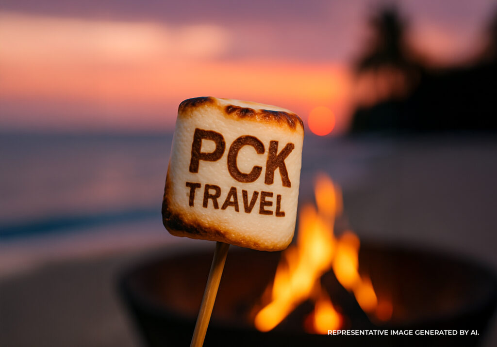 Roasted marshmallow with PCK Travel branding held over a beach bonfire,