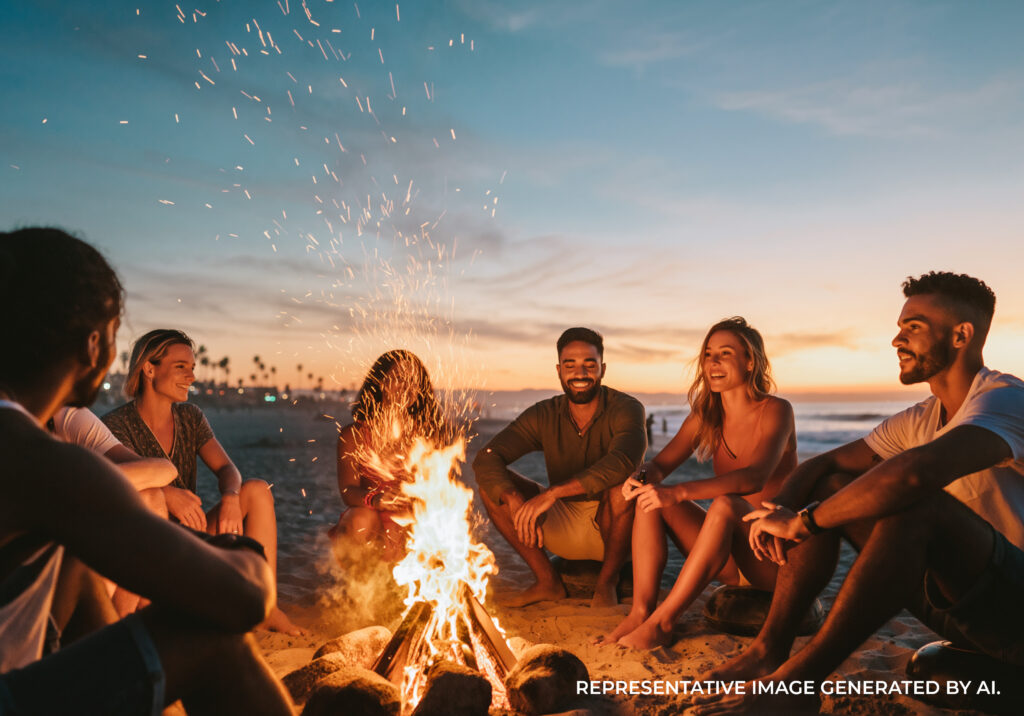 Group of friends around a beach bonfire at sunset at California coastal hangout.