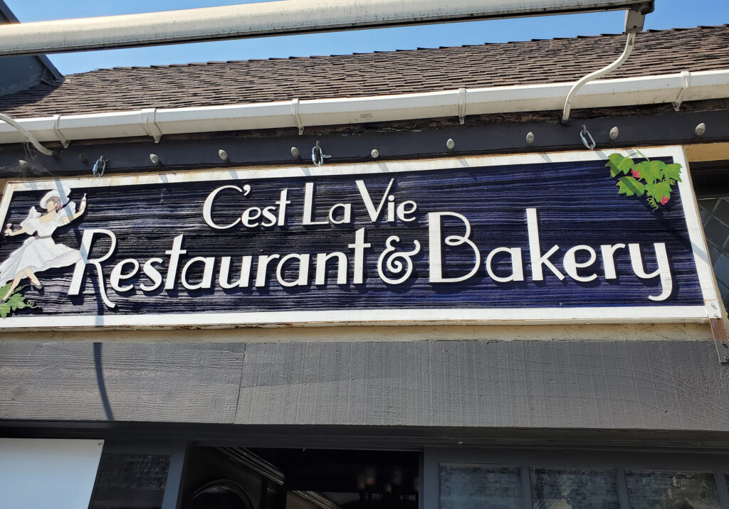 C’est La Vie restaurant and bakery storefront in Laguna Beach, California with signage and outdoor seating.