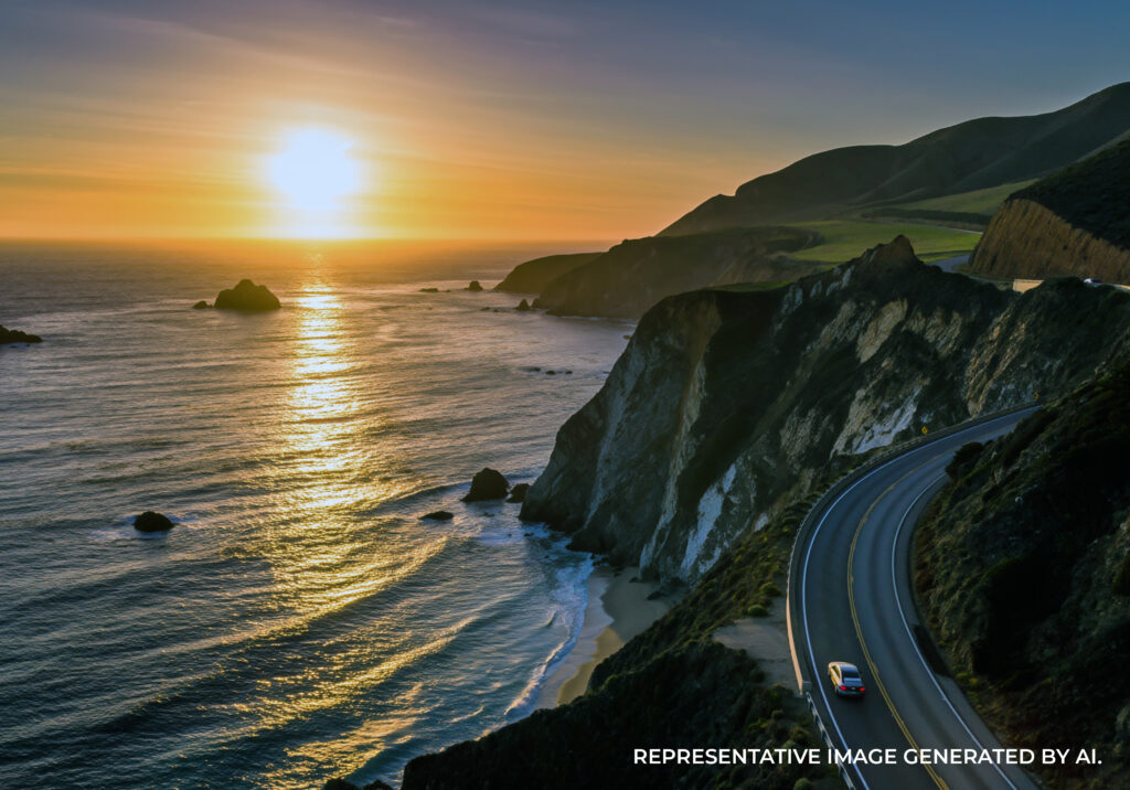 A dramatic sunset over a rocky coastline with cliffs and waves crashing along the shore.