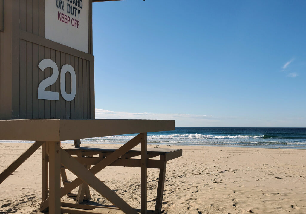 A lifeguard tower overlooking the sandy shoreline at Newport Beach, California with ocean waves in the background.