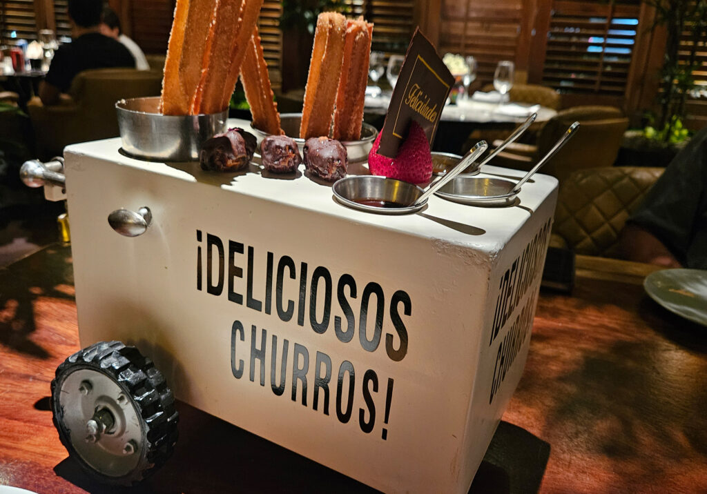 A display of warm churros at a dessert stand in Puerto Vallarta with dipping sauces