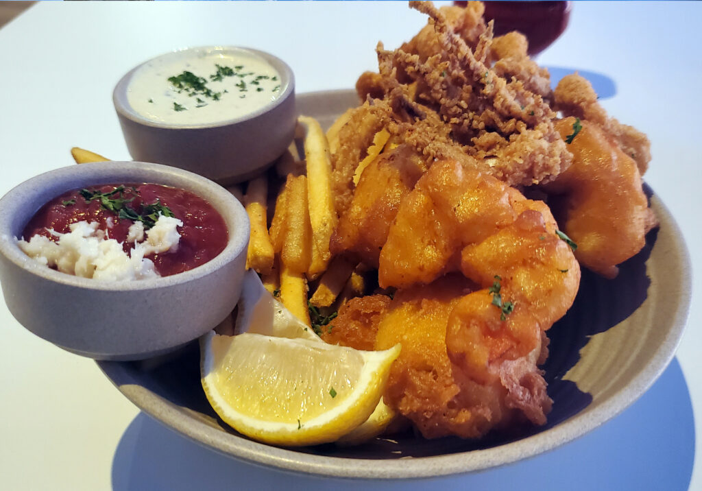 Close up of fish and chips plate with fries lemon and dipping sauces at a San Diego restaurant