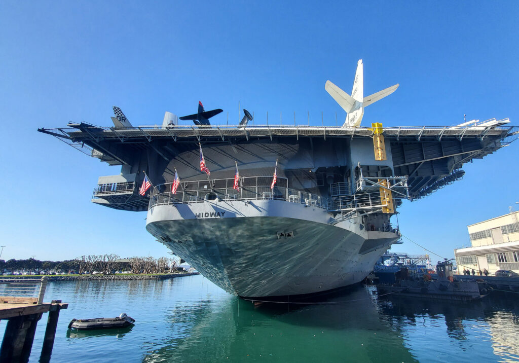 USS Midway aircraft carrier docked on San Diego’s waterfront with planes displayed on the flight deck.