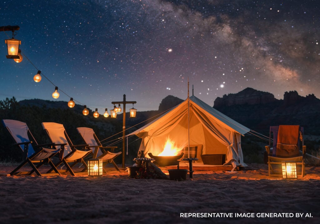 Large illuminated tents set in a desert landscape at night with red rock formations and stars in the sky.