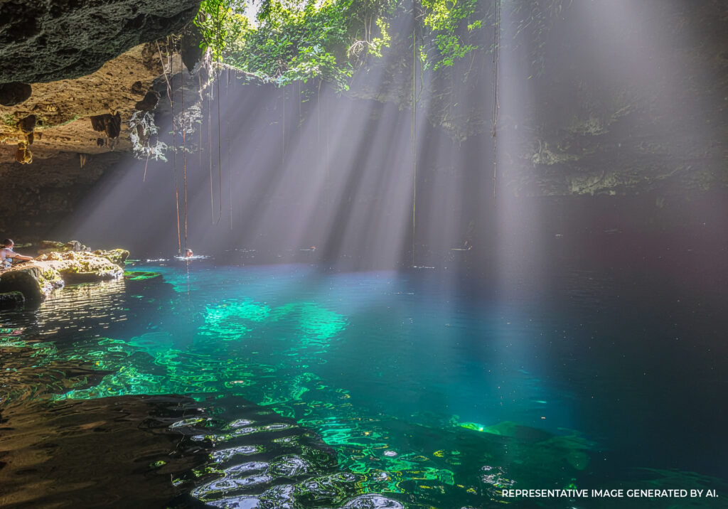 Cenote lagoon with turquoise water surrounded by trees and rocky cliffs in Tulum Mexico