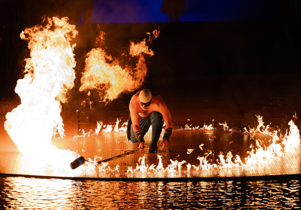 Cirque du Soleil O fire performer creating a ring of flames over water in Las Vegas.