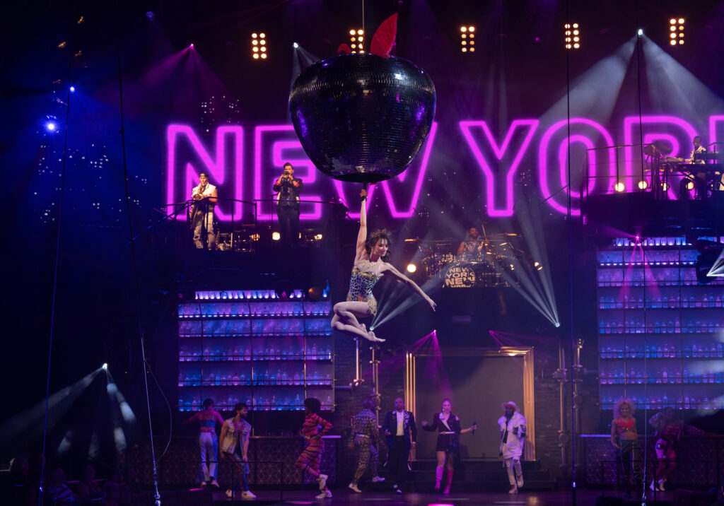 Mad Apple Cirque du Soleil performers in front of New York City neon stage backdrop at New York-New York Hotel in Las Vegas