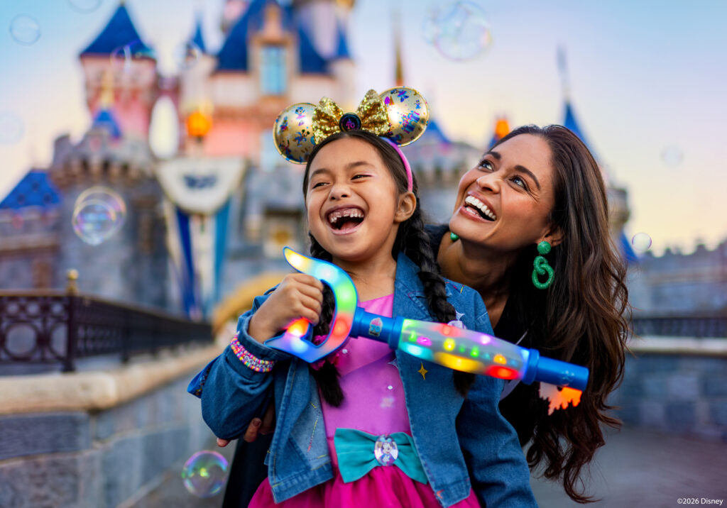 Guests smiling in front of Disneyland castle during the 70th anniversary celebration