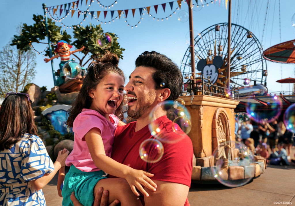 Father and daughter smiling together at Pixar Pier during Disneyland anniversary celebration