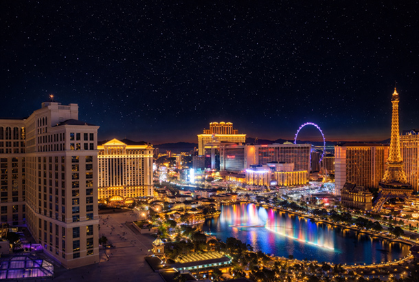 Las Vegas Strip at night with illuminated hotels, fountains, and skyline reflections.