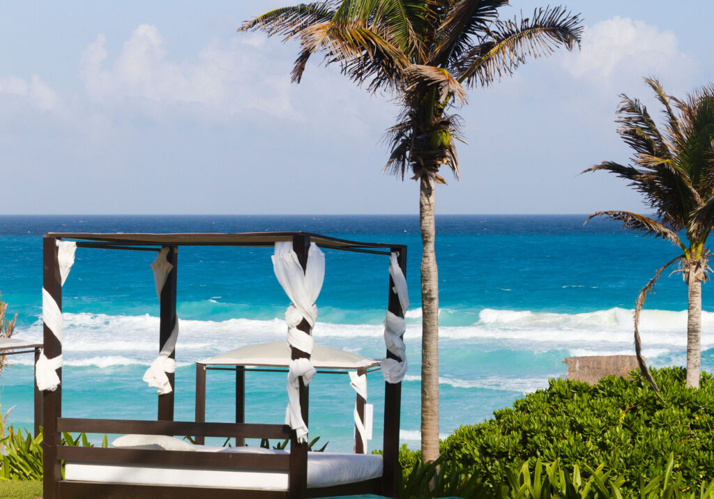 Beachside daybed with flowing curtains and ocean view surrounded by palm trees