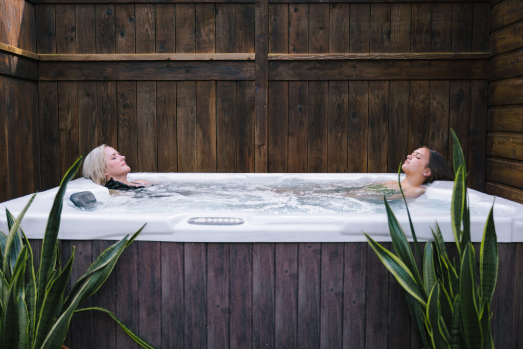 Guests relaxing in outdoor hot tub surrounded by wood and natural elements