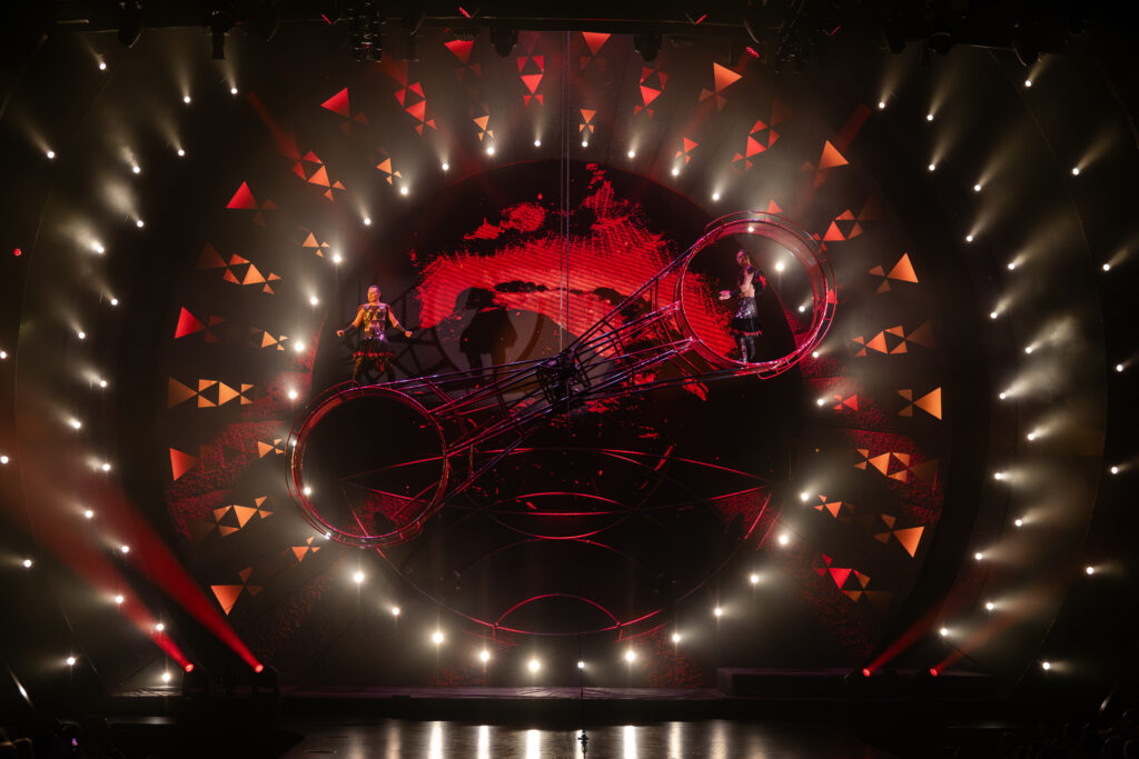 ʻAuana by Cirque du Soleil fire performance with rotating stage and performers in a dramatic red-lit theater setting
