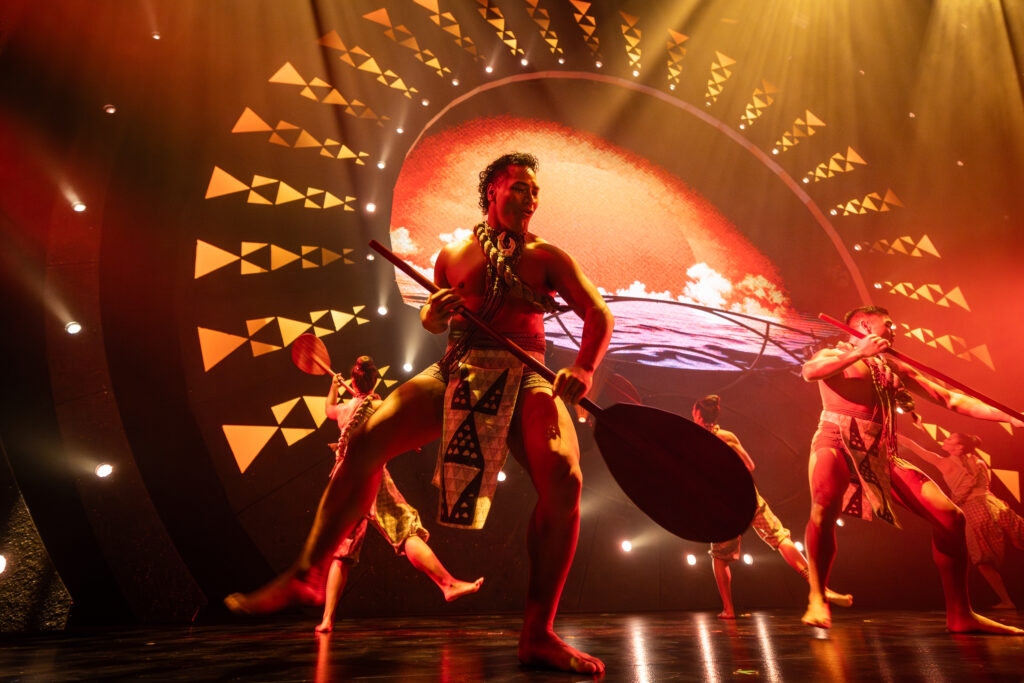 ʻAuana by Cirque du Soleil hula performance with dancers and paddles in a warm-lit stage inspired by Hawaiian culture