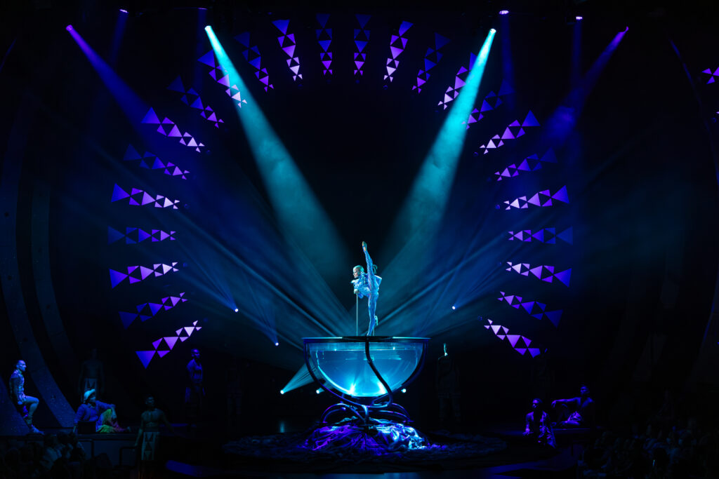ʻAuana by Cirque du Soleil water bowl performance with aerial dancer in a blue-lit stage setting in Waikīkī