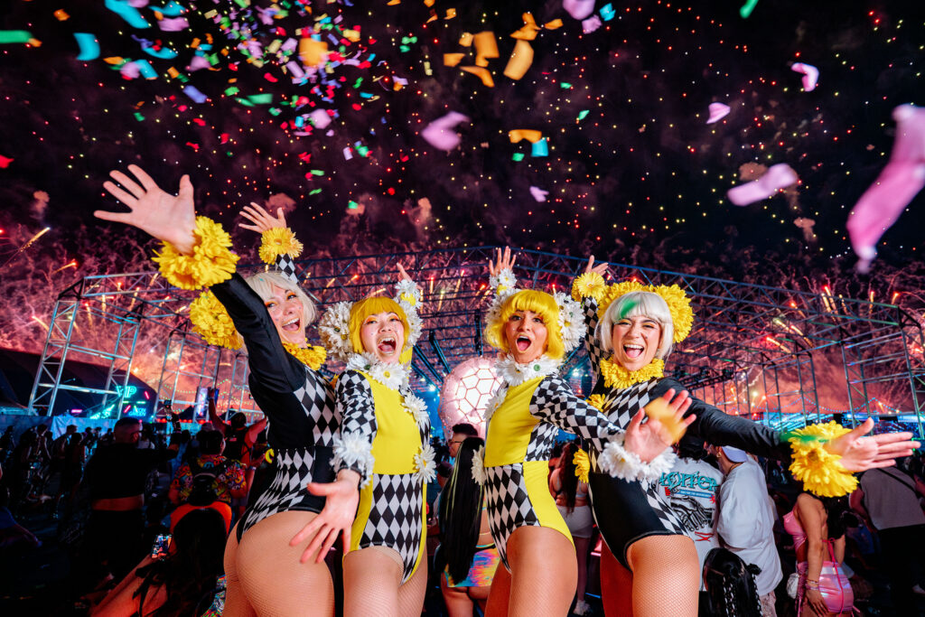 Electric Daisy Carnival Las Vegas crowd with hands raised under colorful lights
