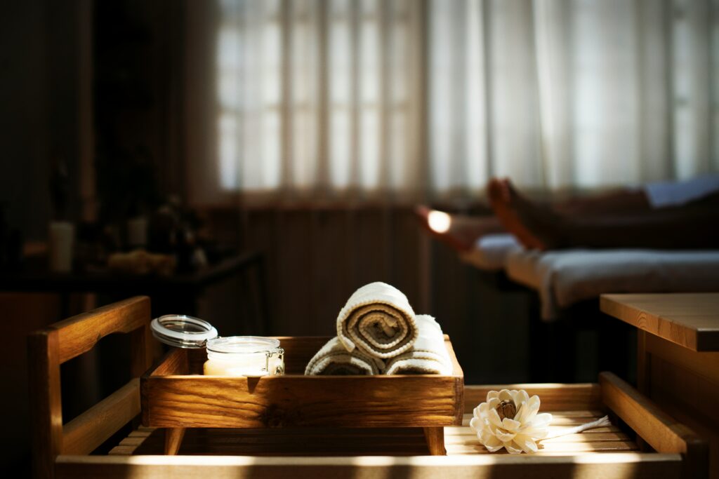 Spa treatment room with rolled towels, candle, and massage setup in soft natural lig
