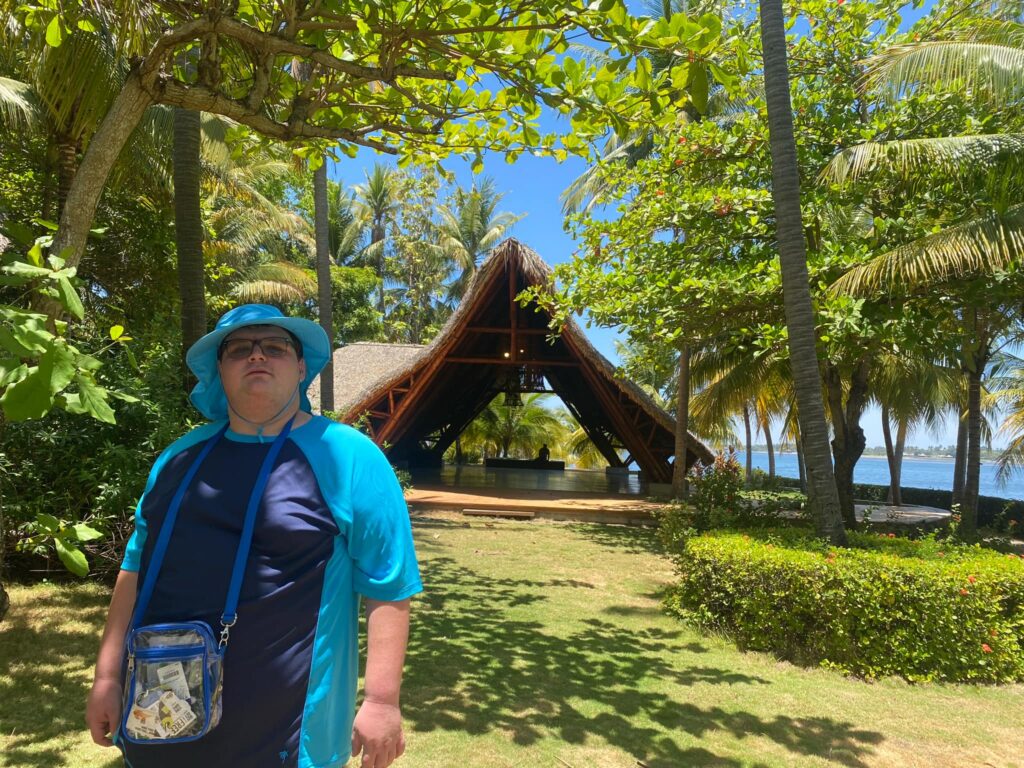 Wyatt Mytel standing near a shaded beach hut in a tropical setting