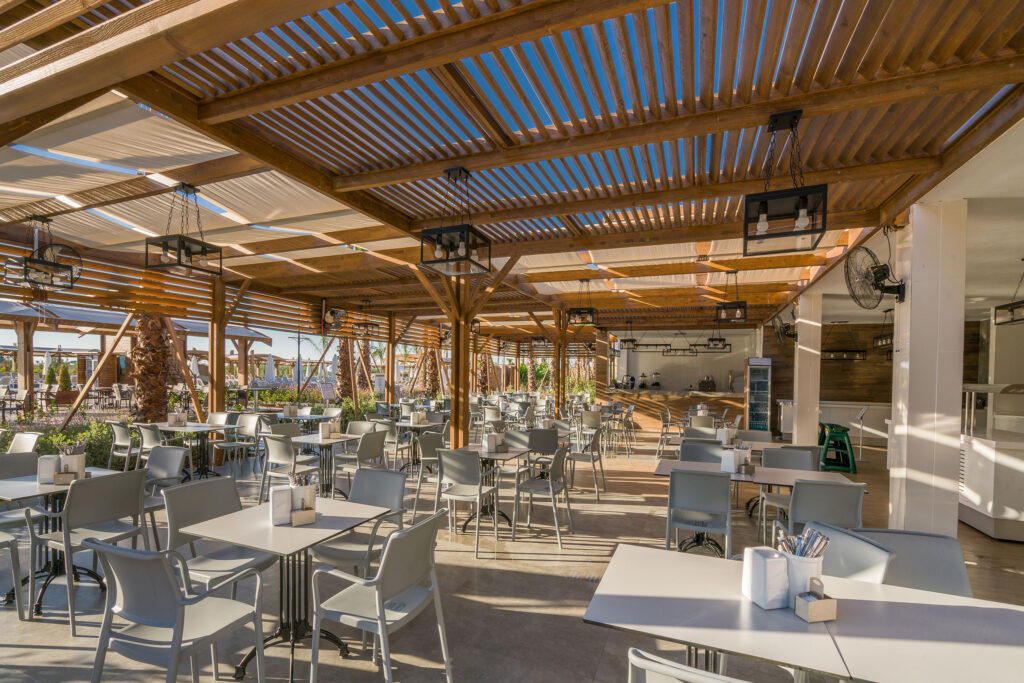 Open-air coastal restaurant with modern seating and wood pergola design near the beach