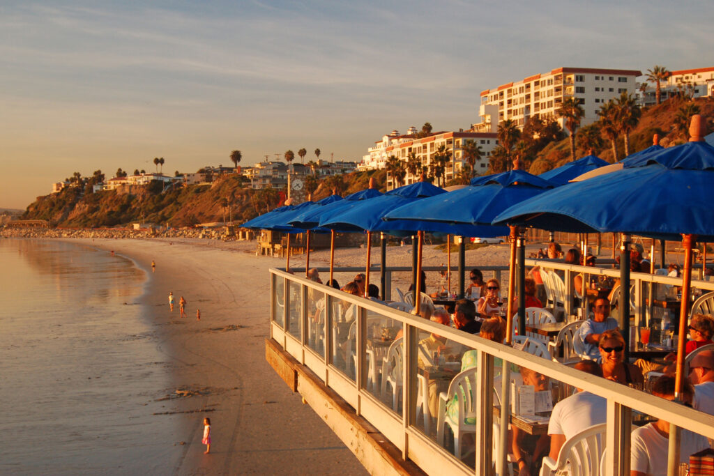 Beachfront restaurant with ocean views and outdoor dining along a coastal shoreline at sunset