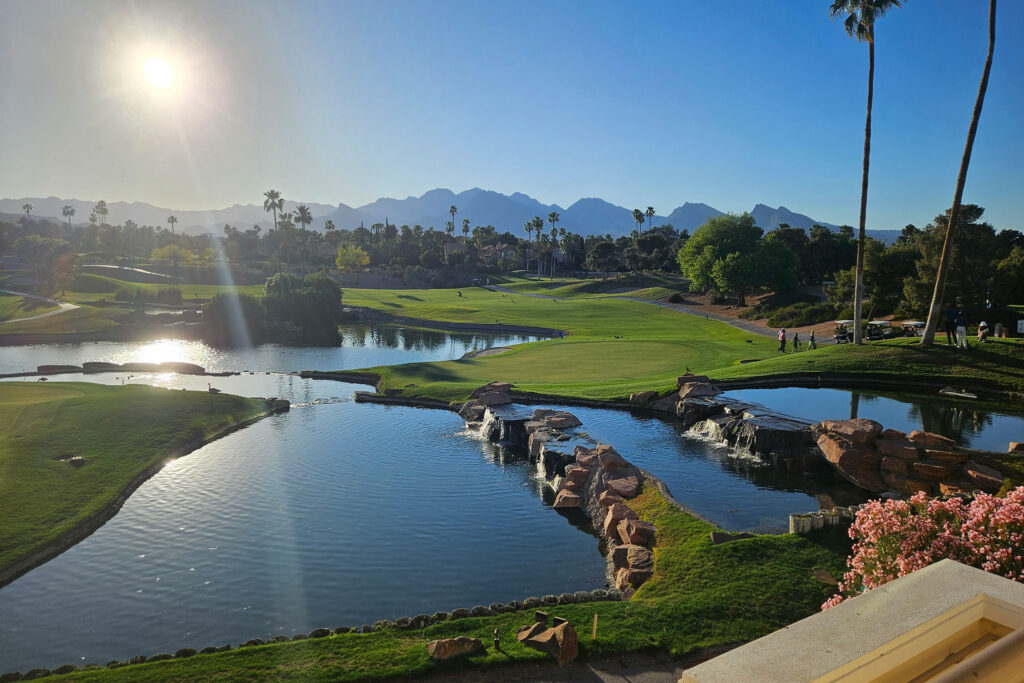 Sunlit golf course with water features, fairways, and mountains at Canyon Gate