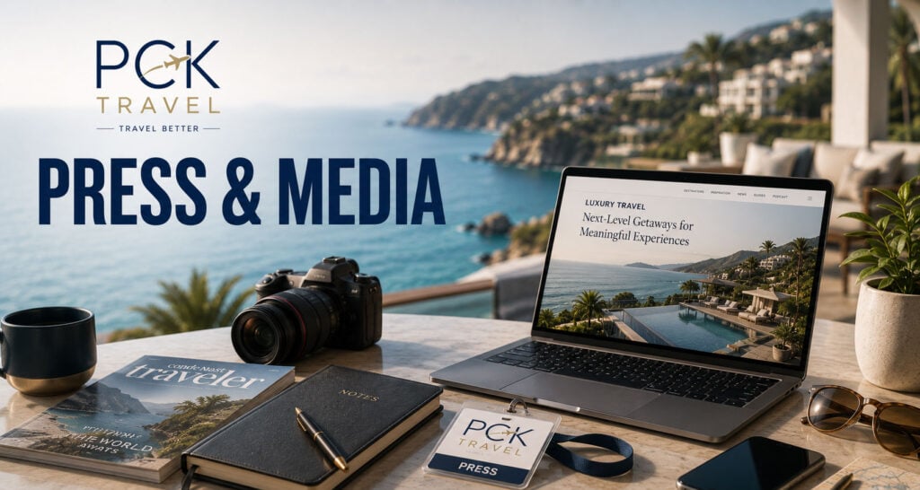 Wide PCK Travel™ Press & Media banner featuring a luxury oceanfront terrace with scenic coastline views. A laptop displaying travel content, professional camera, travel magazine, notebook, press badge, sunglasses, and mobile phone sit on a marble table beneath the “Press & Media” headline.