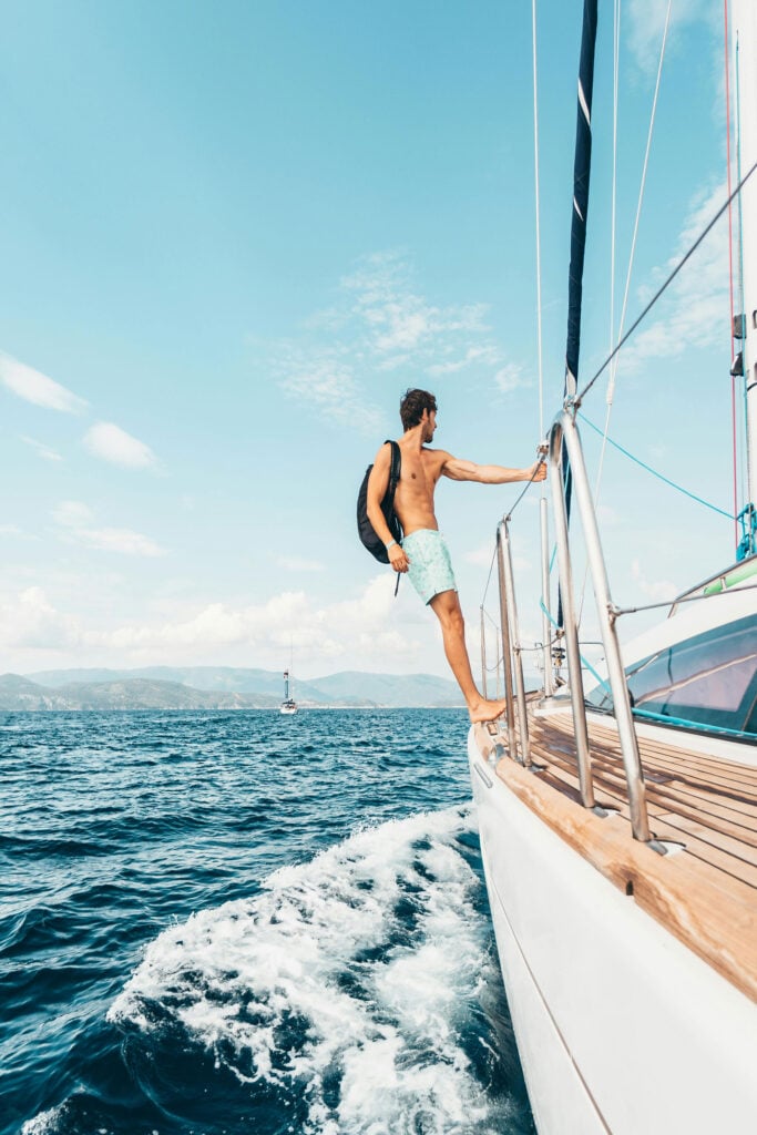 Traveler standing on a sailboat surrounded by open ocean views